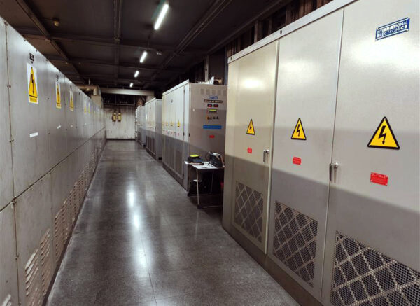 A technical corridor housing a subsynchronous cascade unit alongside multiple electrical cabinets and auxiliary components used for controlling high‑power slip ring motor systems in industrial environments.